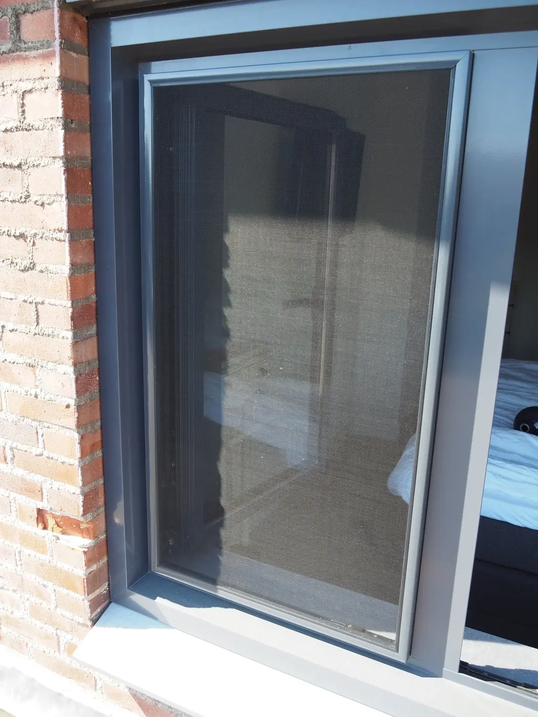 Inzethor in een slaapkamerraam in een bakstenen gevel