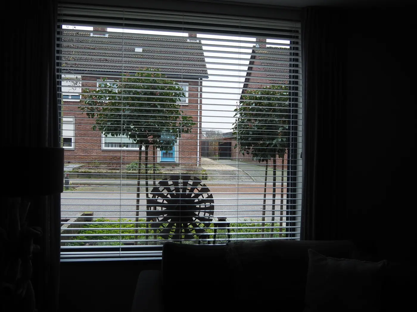 Houten jaloezieën voor een woonkamerraam met uitzicht op straat