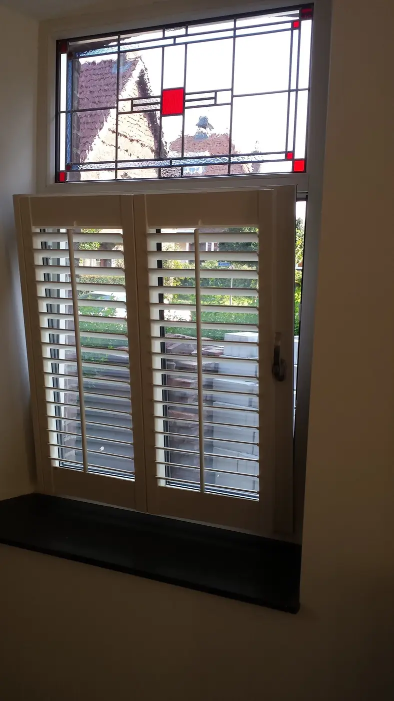 Shutters onder een glas-in-loodraam, in twee delen te bedienen