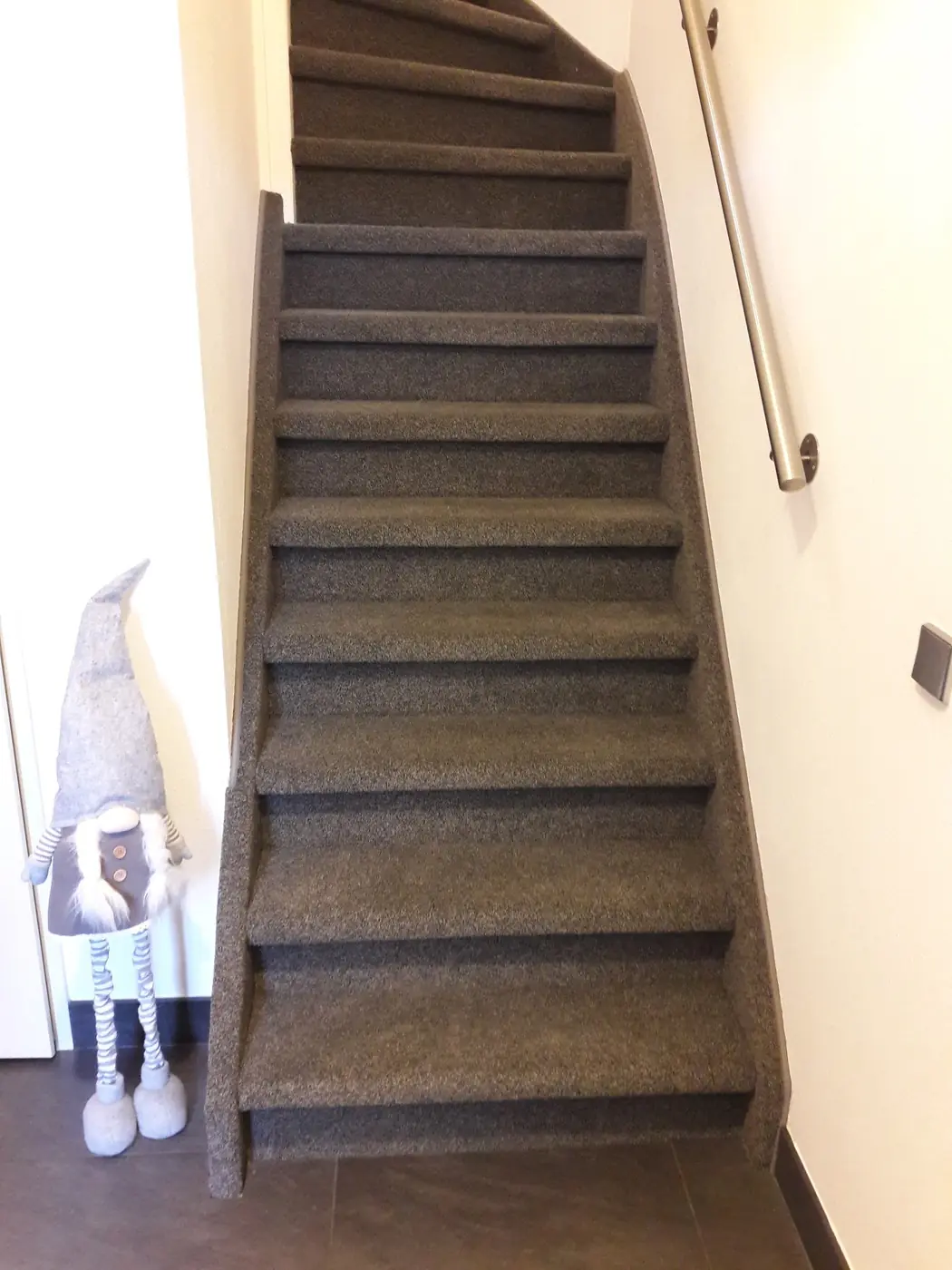 Bruin tapijt op een open trap met houten leuning